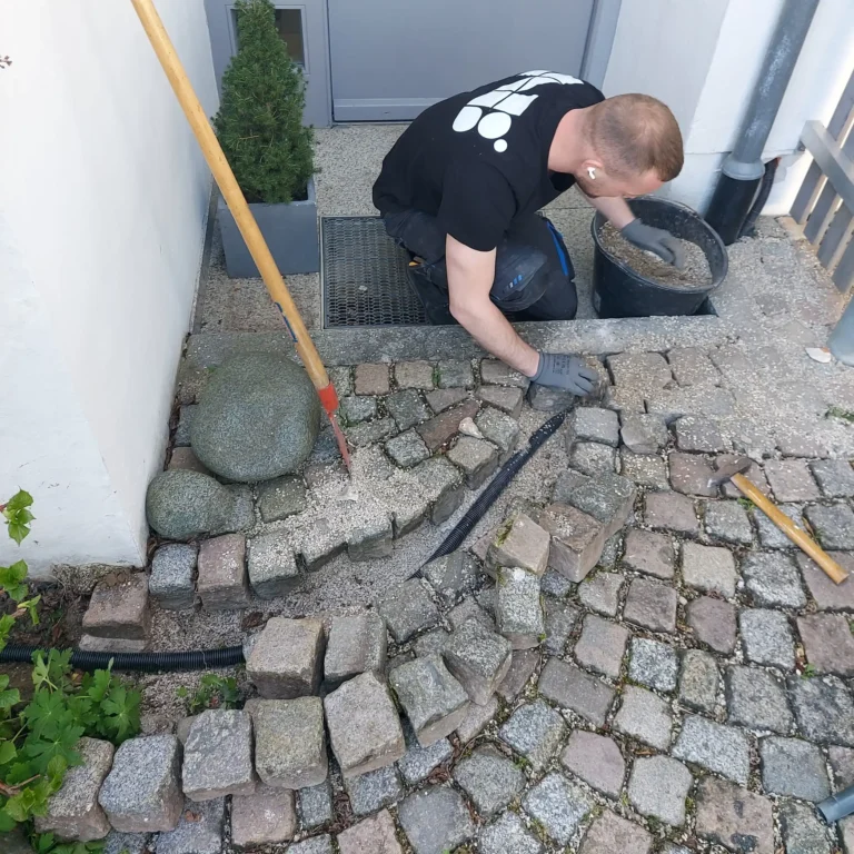 Techniker verlegt Stromkabel für Wallbox unter Pflastersteinen im Rahmen der schlüsselfertigen Photovoltaik-Montage