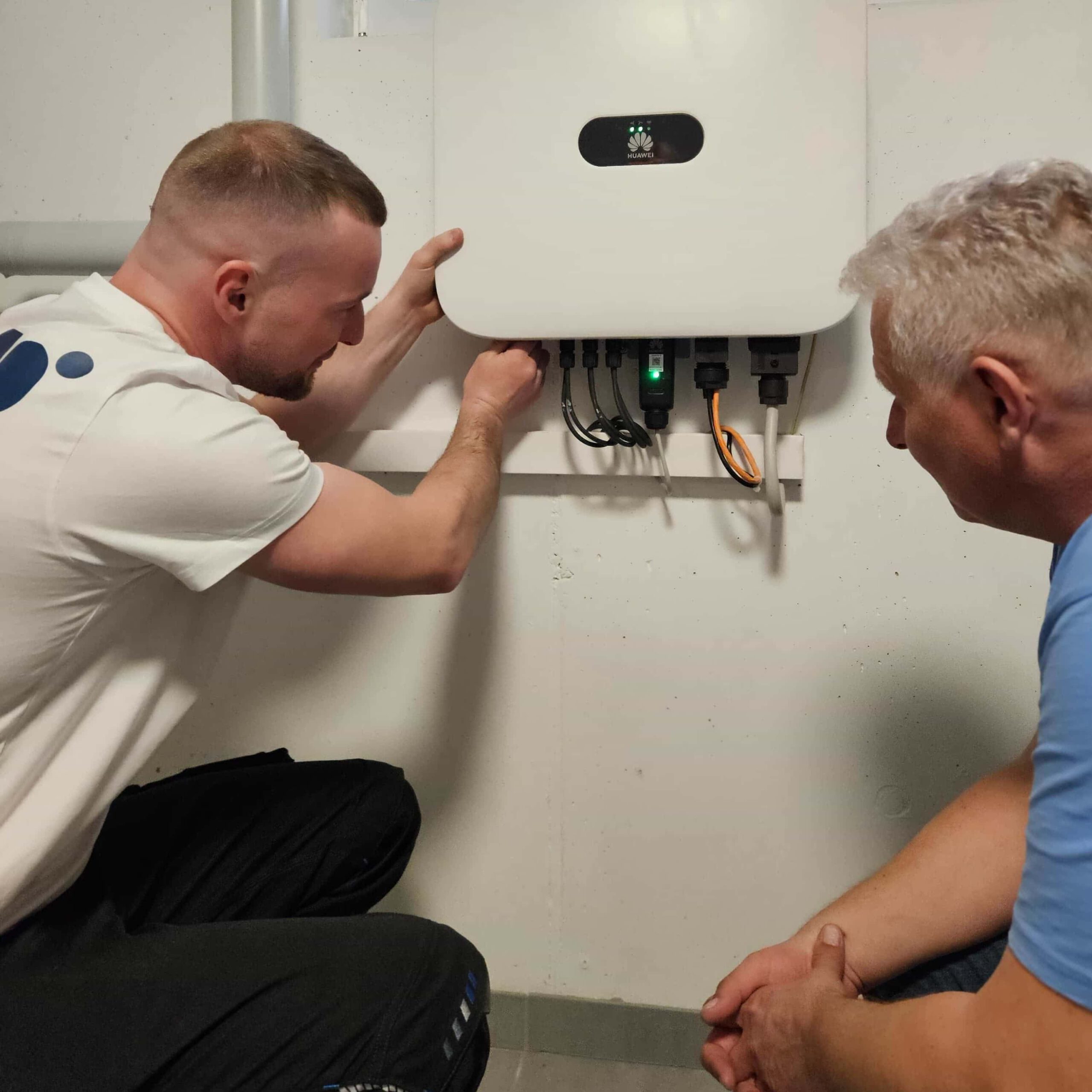 Ein nbg solar Techniker nimmt vor einem Kunden in einem Haus in Nürnberg einen Huawei-Wechselrichter in Betrieb und erklärt Schritt für Schritt die Bedienung der Anlage und App.